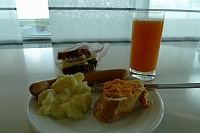  German sausage, potato salad, bread with peperoni spread, vegetarian sandwich and glass of fruit juice at Lufthansa Business Lounge