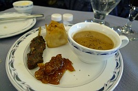  A demitasse of morel mushroom soup accompanied by seafood-filled pastry and lamb kabob with eggplant mango chutney