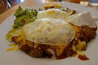  Papas and Huevos at Taos Diner - Taos, NM: Home fries smothered in red and green chile, then topped with melted cheddar-jack cheese and two eggs over-medium.  Served with sour cream and guacamole.