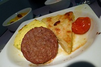  First Class breakfast service: egg omelette, sausage, cheesy potatoes, and roasted cherry tomato