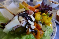  Appetizer of prosciutto, melon, and roasted red pepper with parmesan cheese and balsamic reduction