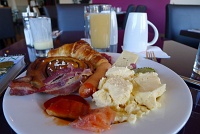  Sheraton Breakfast Buffet: Tomato herring, gravad lax, scrambled eggs, Swedish sausage, bacon, Swedish sweet pickle, salami with cheese, cinammon roll, croissant with lingonberry marmalade, and apple juice