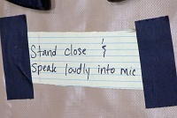  Sign beneath microphone at Centennial Lecture Series, Tudor Fieldhouse