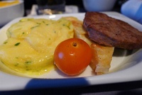  First Class breakfast: herbed egg omelette, roasted cherry tomato, potato wedge, and turkey sausage