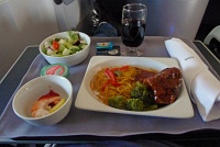  First class dinner: Asian short ribs with noodles, broccoli, shrimp cocktail, salad with ranch dressing, and dinner role with butter